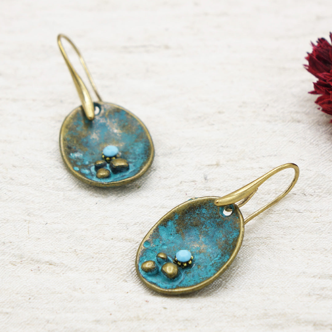 Pair of earrings with blue and gold design on a textured white surface.