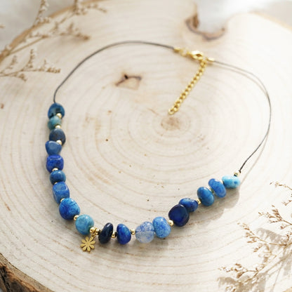 Necklace with blue beads and gold accents on a wooden surface