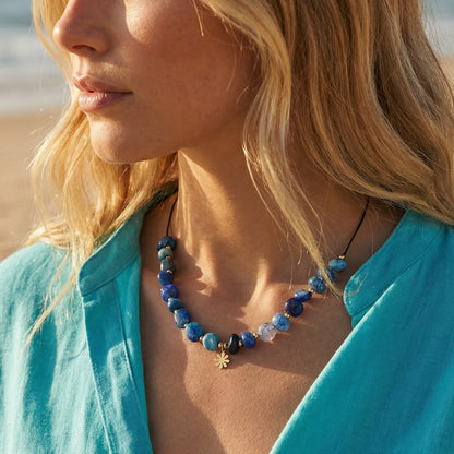 Woman wearing a blue beaded necklace on a beach