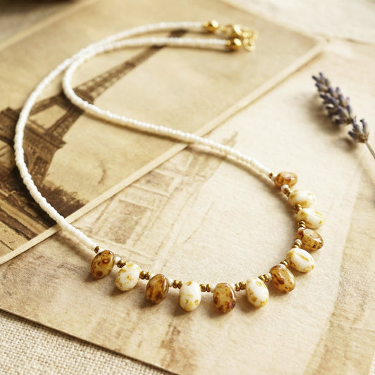 Necklace with brown and white beads on a textured surface with a blurred background