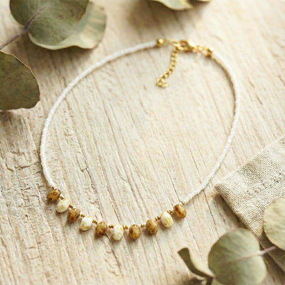 Necklace with beads on a wooden surface with eucalyptus leaves