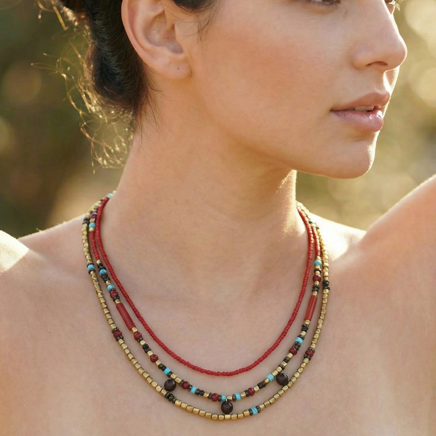 Close-up of a woman wearing a colorful beaded necklace with a blurred natural background