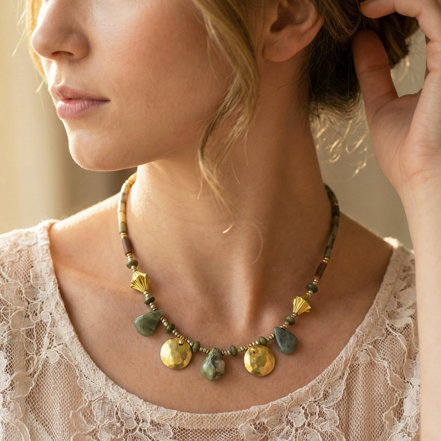 Close-up of a woman wearing a necklace with green and gold stones.