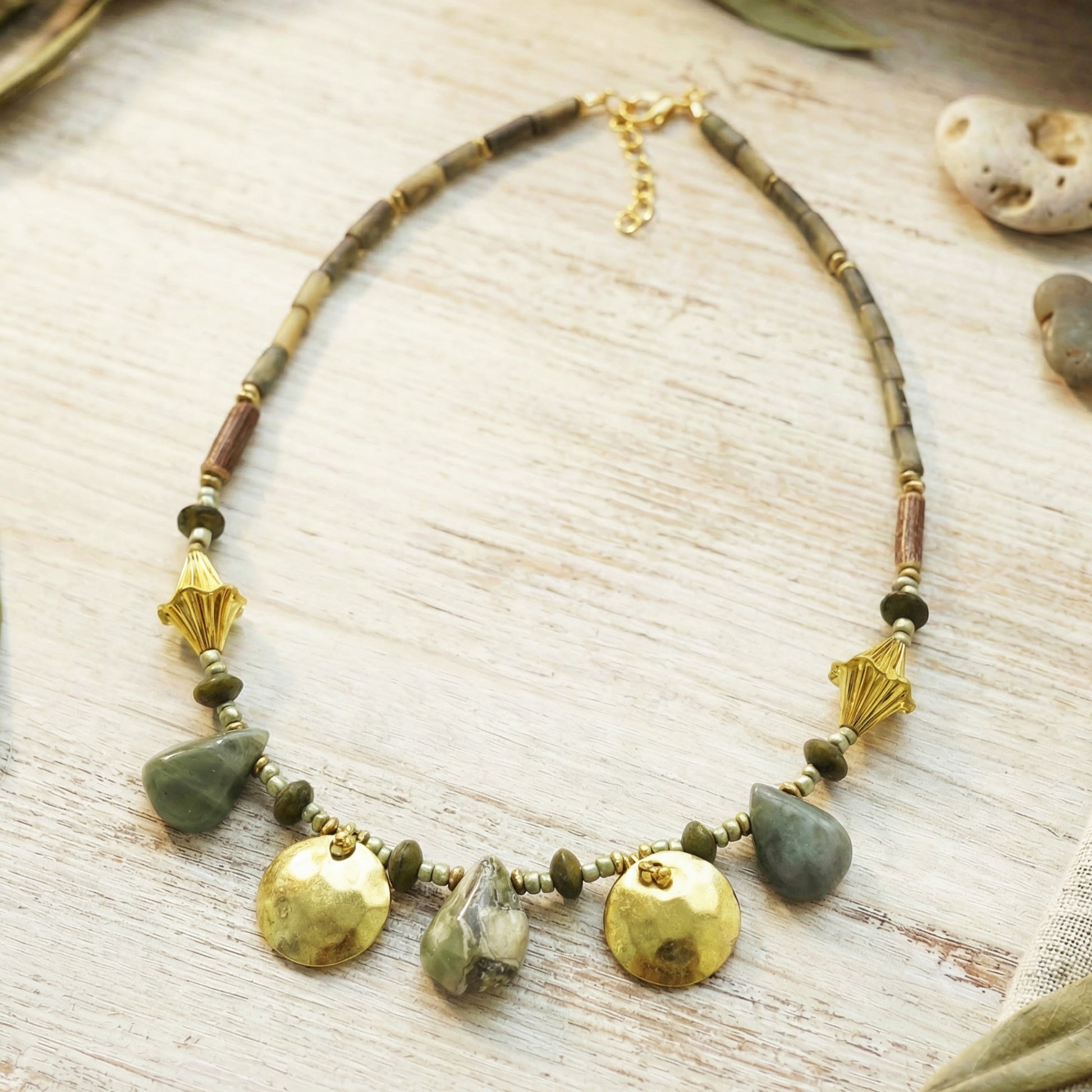 Necklace with green and gold beads on a textured surface