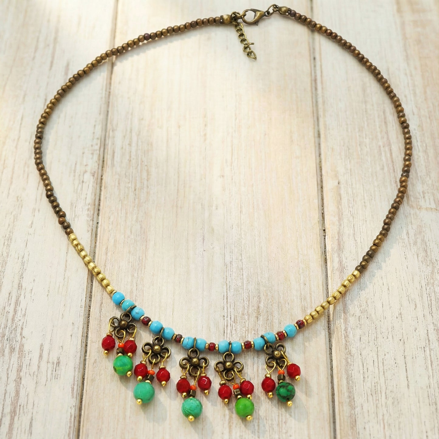 Colorful beaded necklace with floral charms on a wooden surface