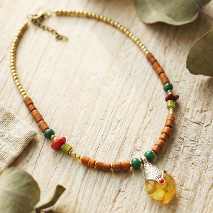 Necklace with beads and a yellow pendant on a wooden surface