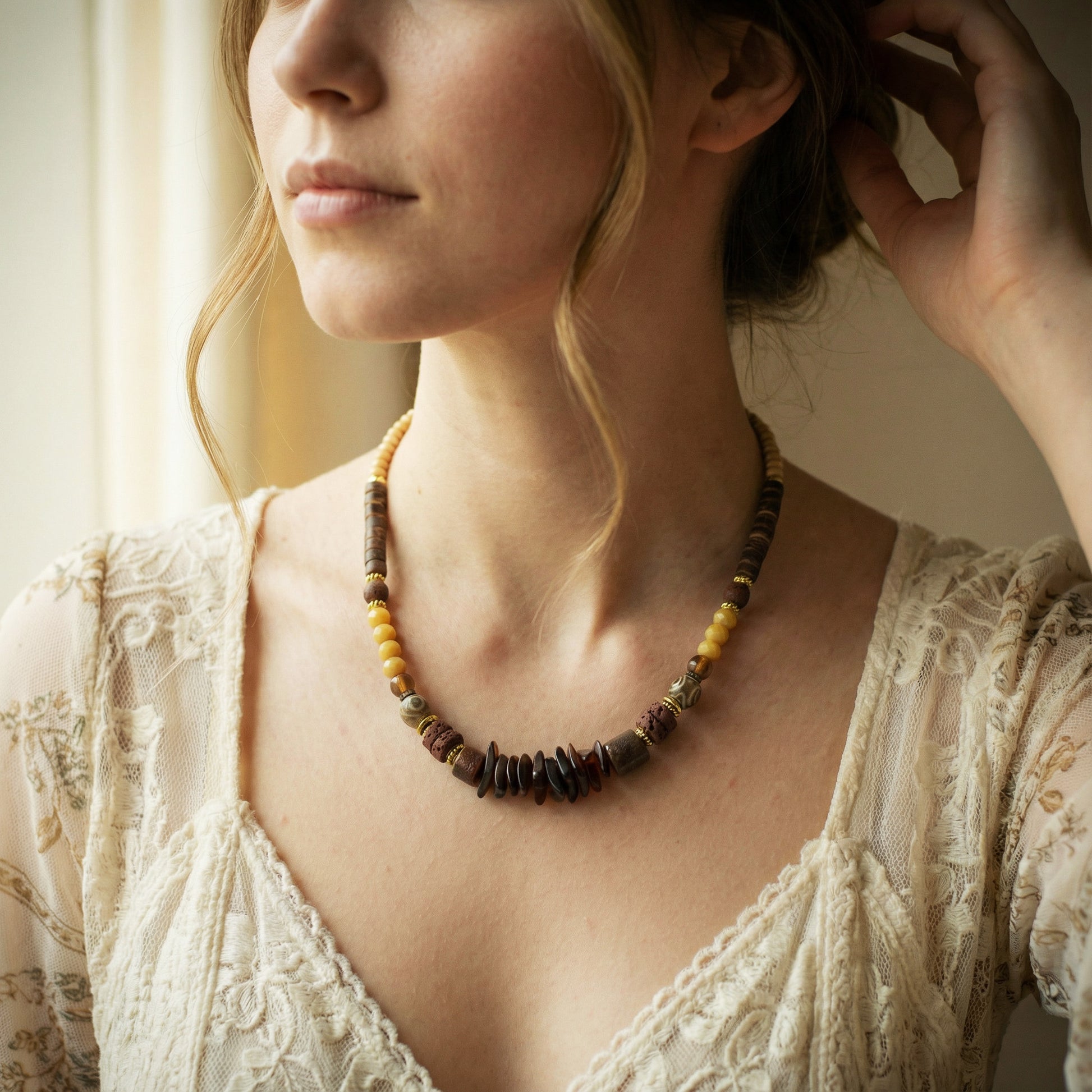 Woman wearing a beaded necklace with a soft, blurred background