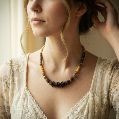 Woman wearing a beaded necklace with a soft, blurred background