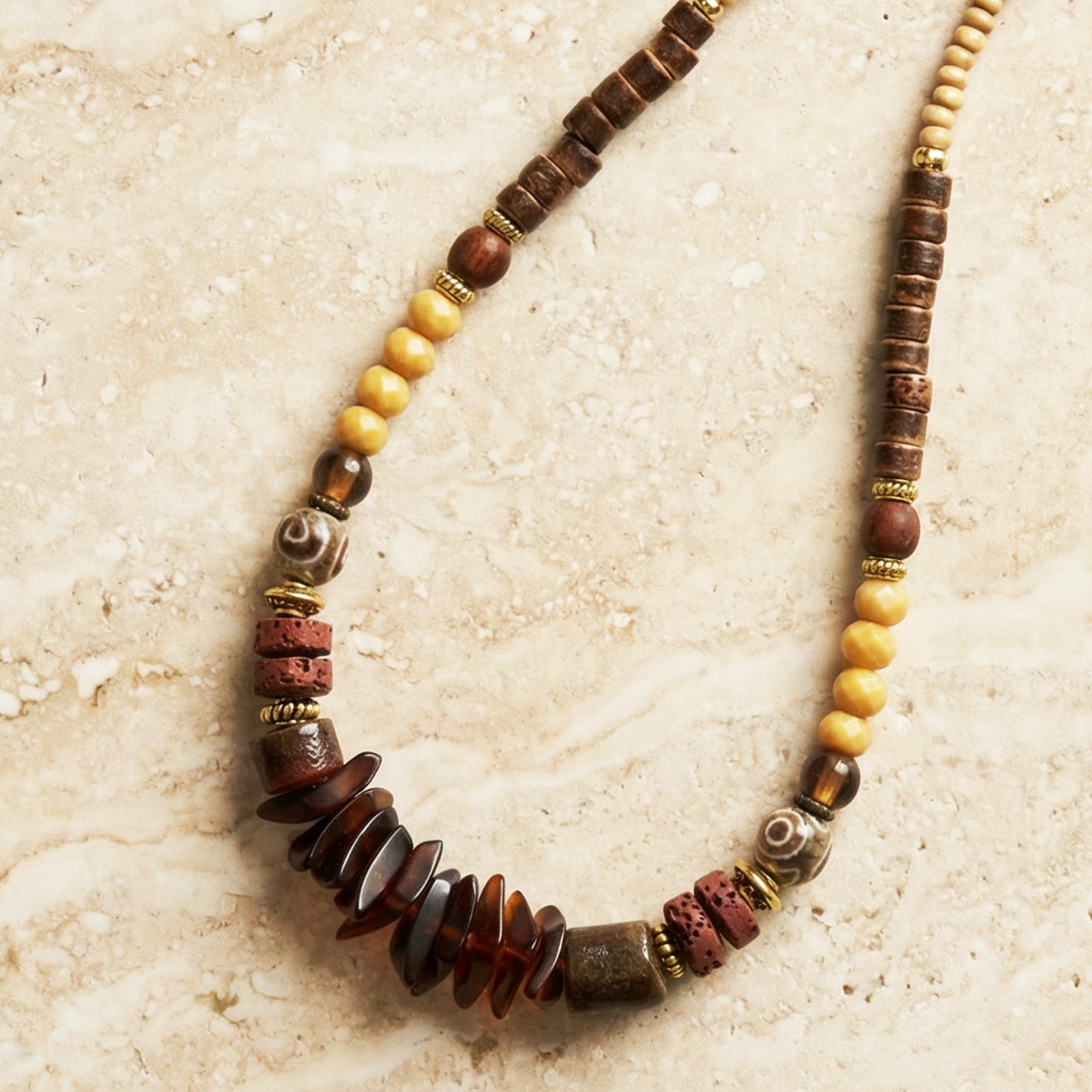 Beaded necklace with brown, yellow, and red beads on a textured beige surface