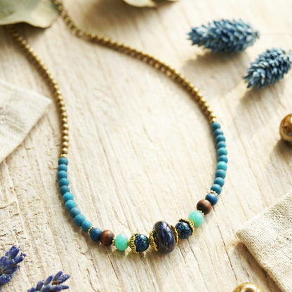 Necklace with blue and brown beads on a wooden surface with lavender flowers