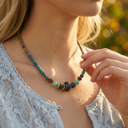 Woman wearing a beaded necklace with a blurred natural background