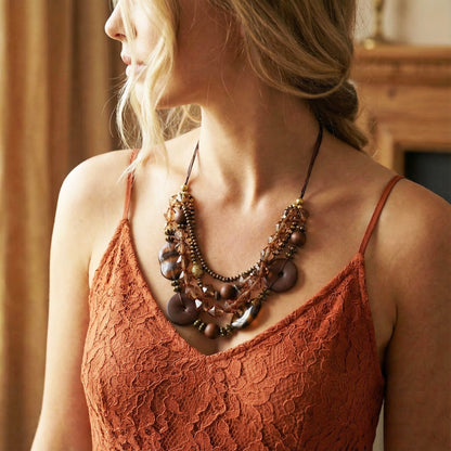 Woman wearing a rust-colored lace top and a large, intricate necklace.