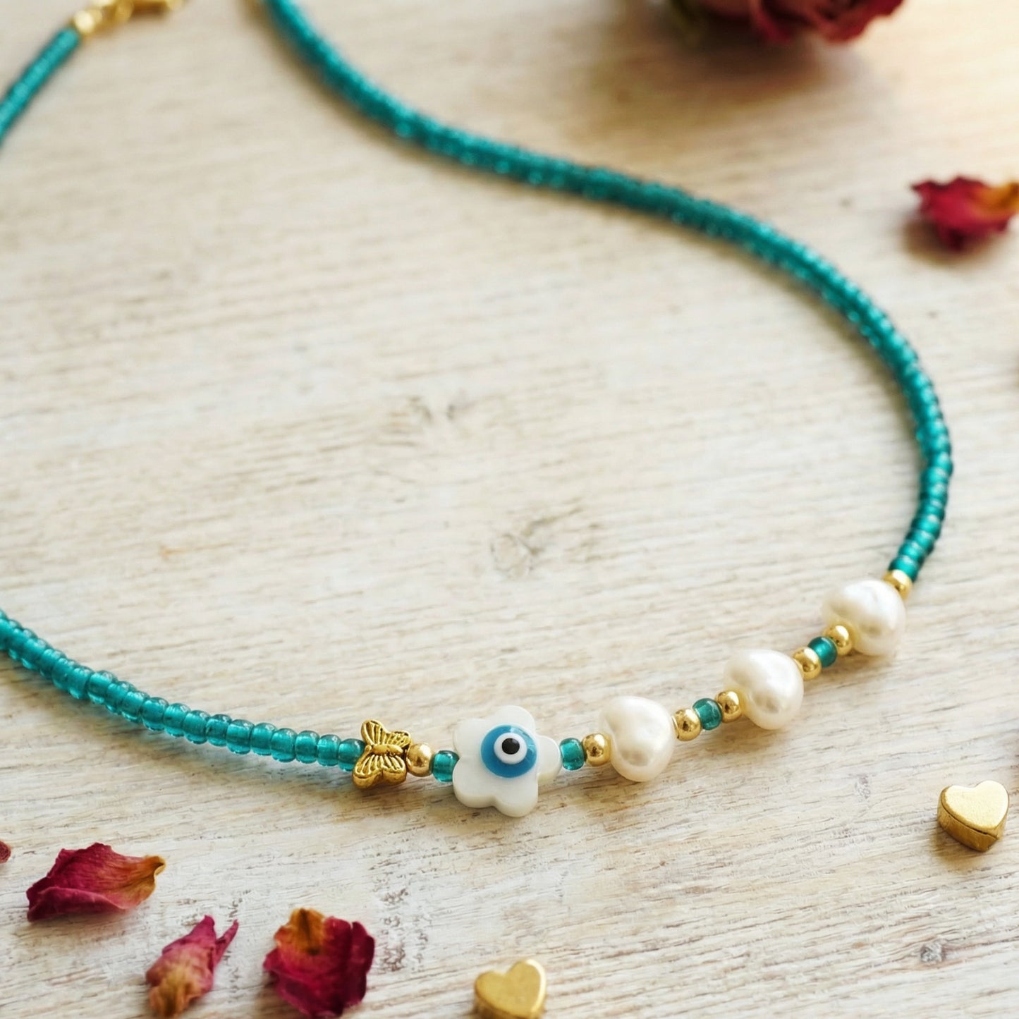 Necklace with turquoise beads, pearls, and decorative elements on a light wooden surface.