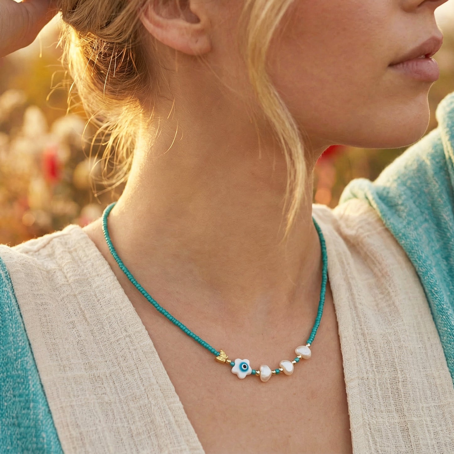Close-up of a woman wearing a turquoise necklace with eye-shaped beads in an outdoor setting.