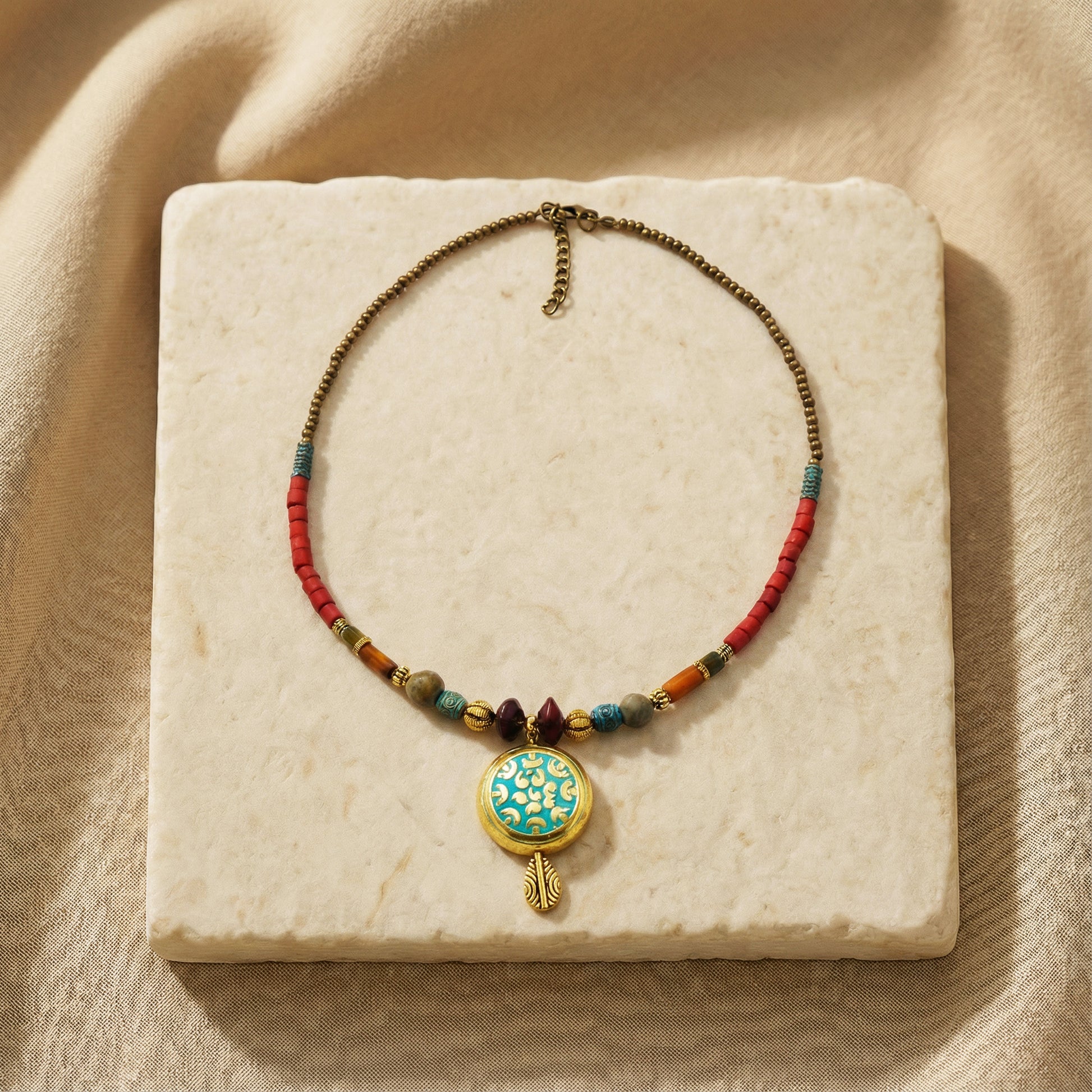 Necklace with colorful beads and a decorative pendant on a beige stone surface