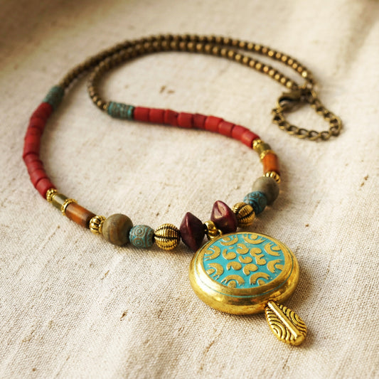 Necklace with colorful beads and a decorative pendant on a textured fabric background