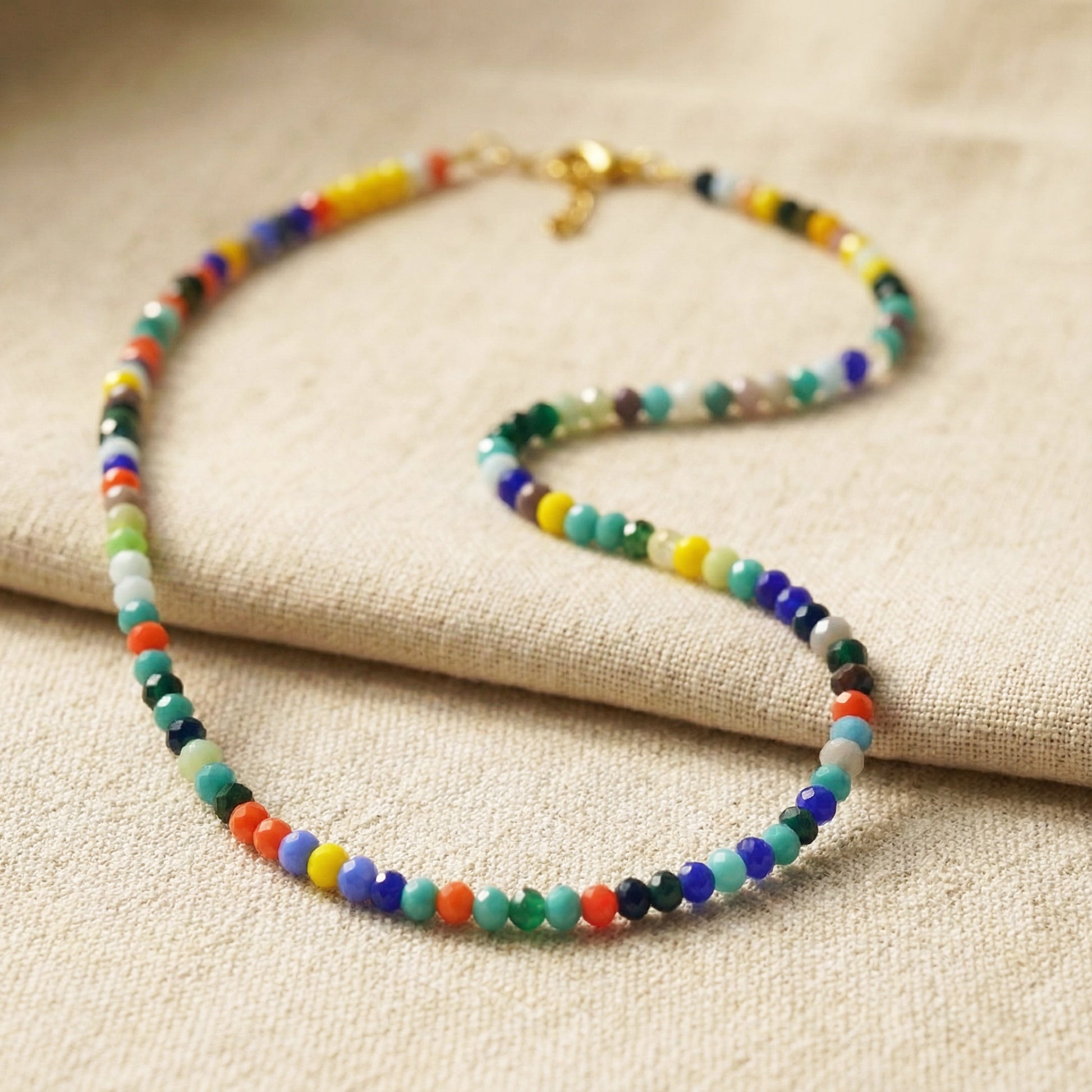 Colorful beaded necklace on a beige fabric background