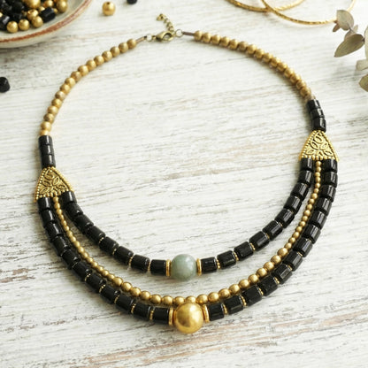 Necklace with black and gold beads on a light wooden surface