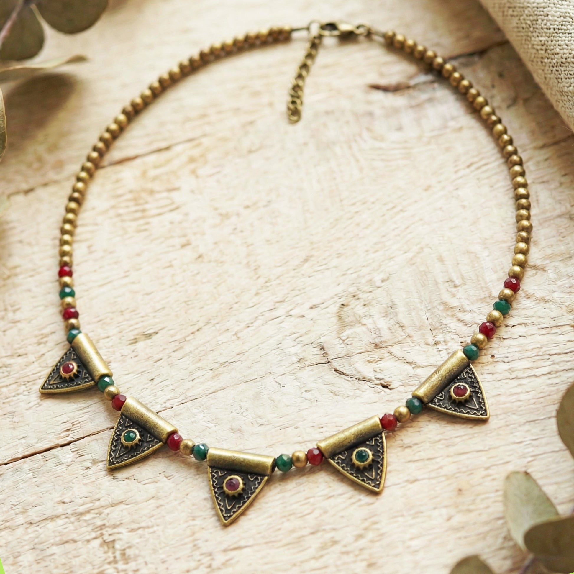 Brass necklace with triangle-shaped pendants on a wooden surface