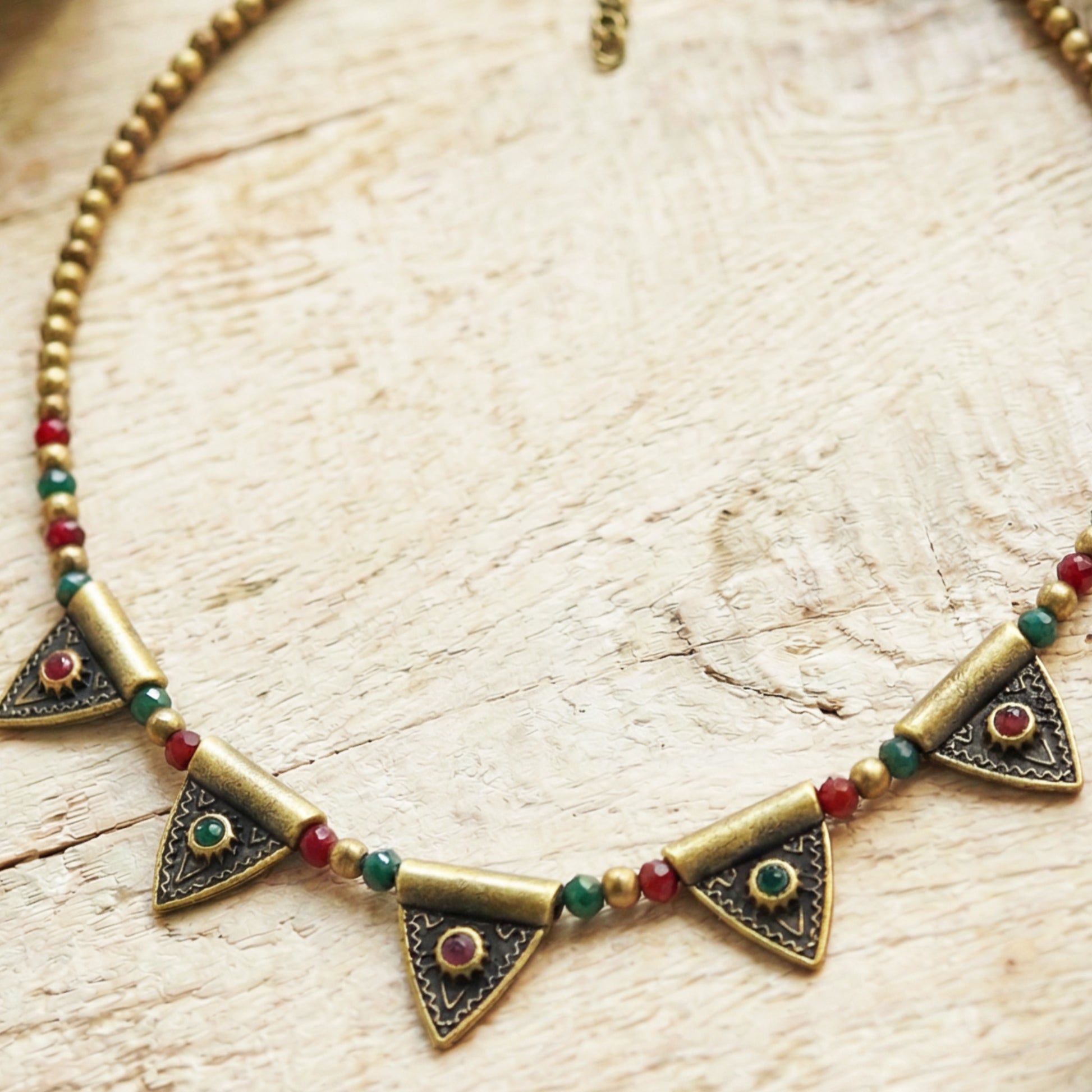 Necklace with triangle-shaped pendants and colored beads on a wooden surface