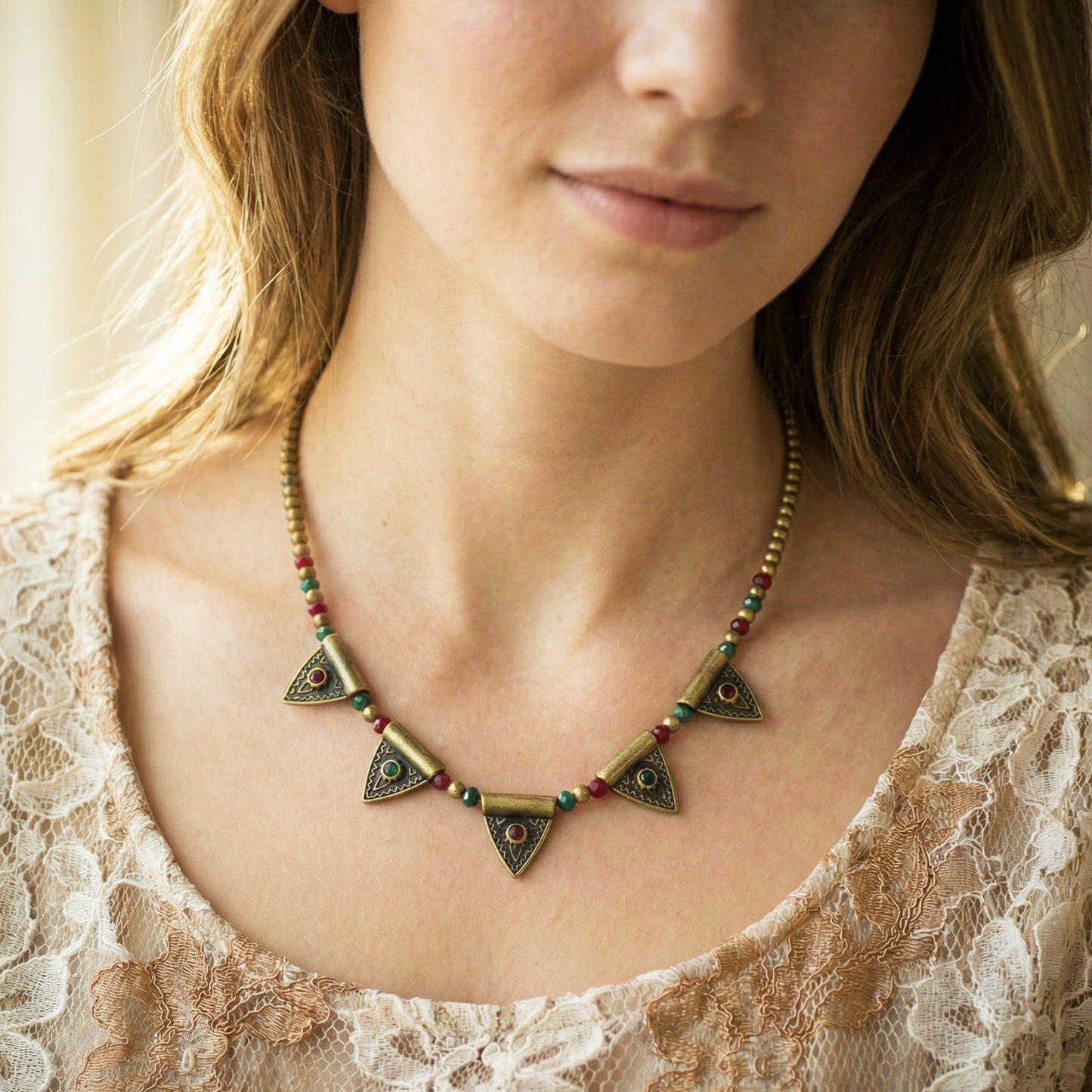 Close-up of a woman wearing a decorative necklace with a lace top.