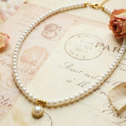 Pearl bracelet with a gold charm on an old letter background