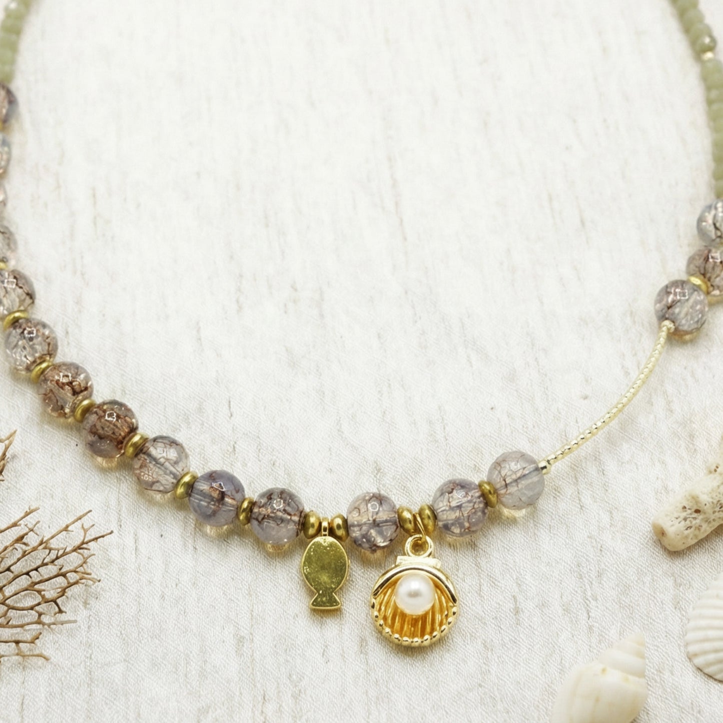 Necklace with beads and charms on a textured white background