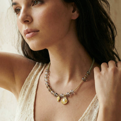 Woman wearing a delicate necklace with a neutral background