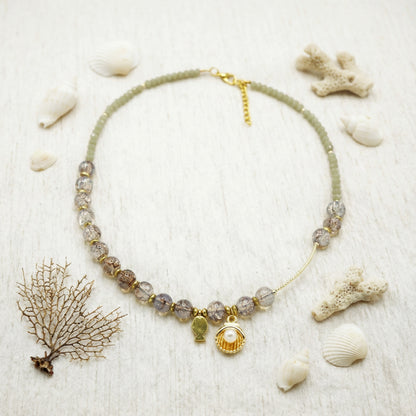 Necklace with shell charm on a sandy background with shells and coral
