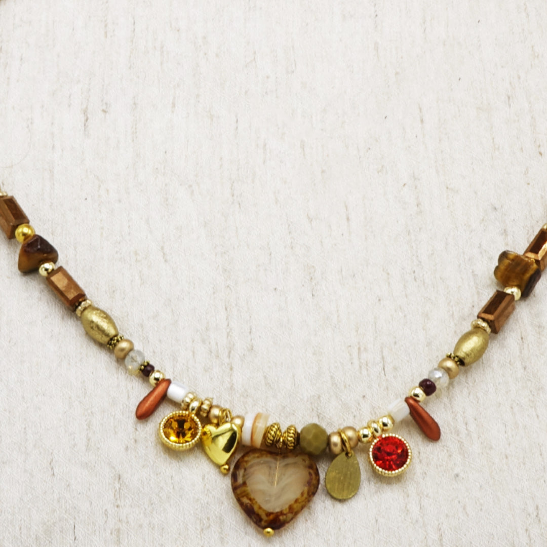 Necklace with various beads and charms on a textured white background