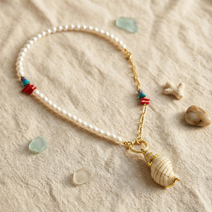 Pearl necklace with a shell pendant on sand