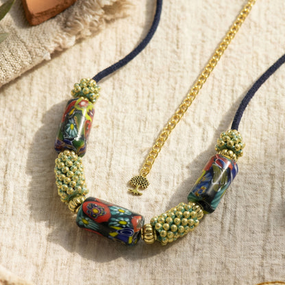 Necklace with colorful beads and gold chain on a textured surface