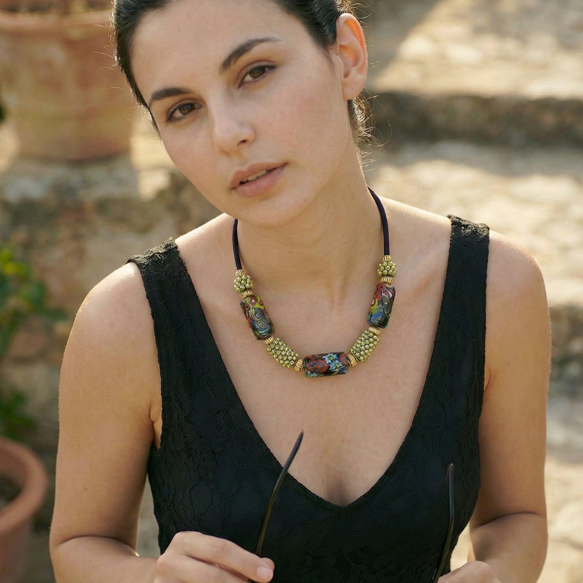 Woman wearing a black dress and colorful necklace outdoors