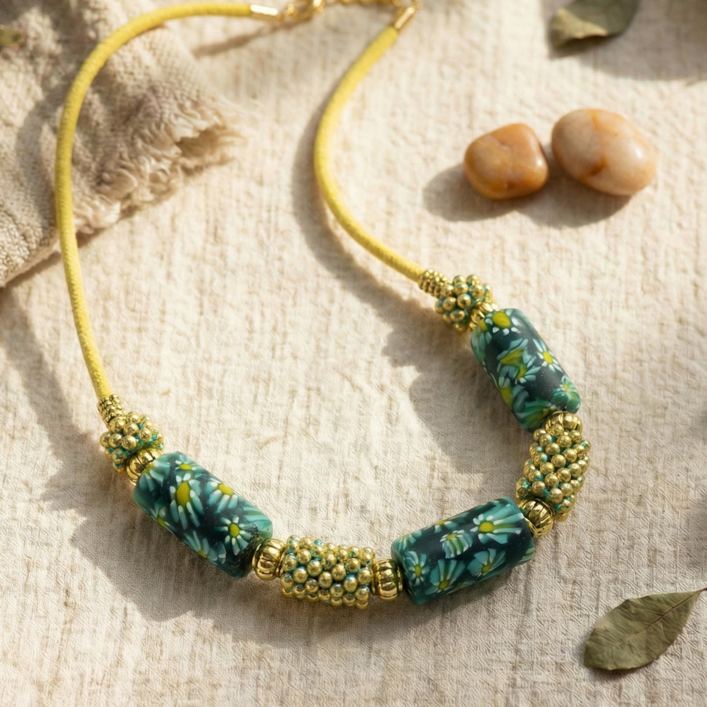 Necklace with green floral beads and gold accents on a textured surface