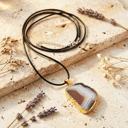 Necklace with agate pendant on a stone surface with lavender flowers