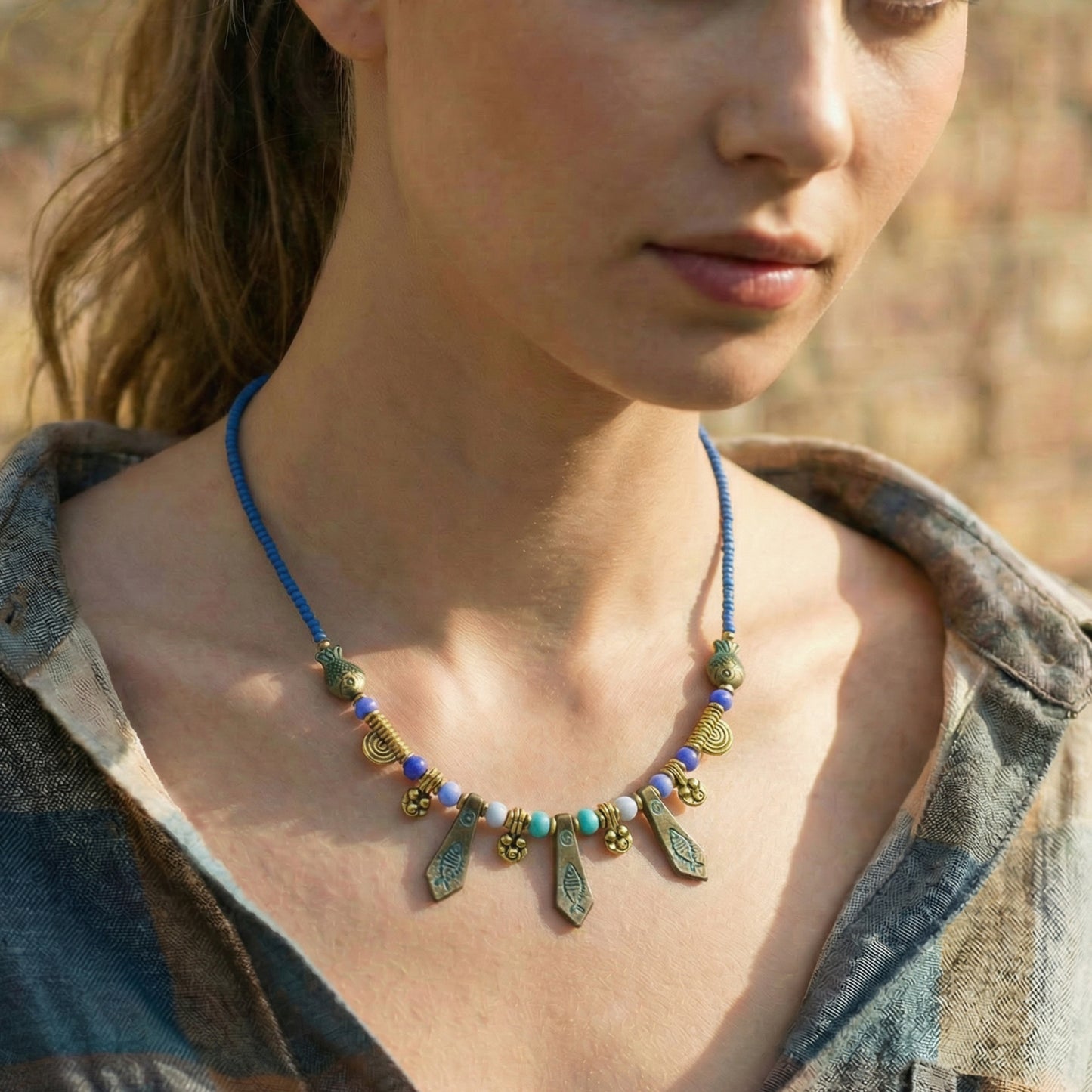 Close-up of a woman wearing a detailed necklace with a blurred natural background