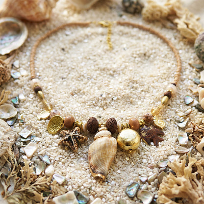 Necklace with seashell and starfish charms on sand and shells