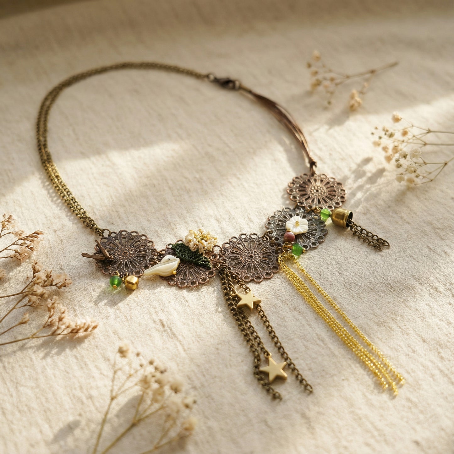 Decorative necklace with tassels on a textured surface with dried flowers