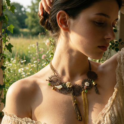 Woman wearing a decorative necklace in a natural setting with greenery and flowers.