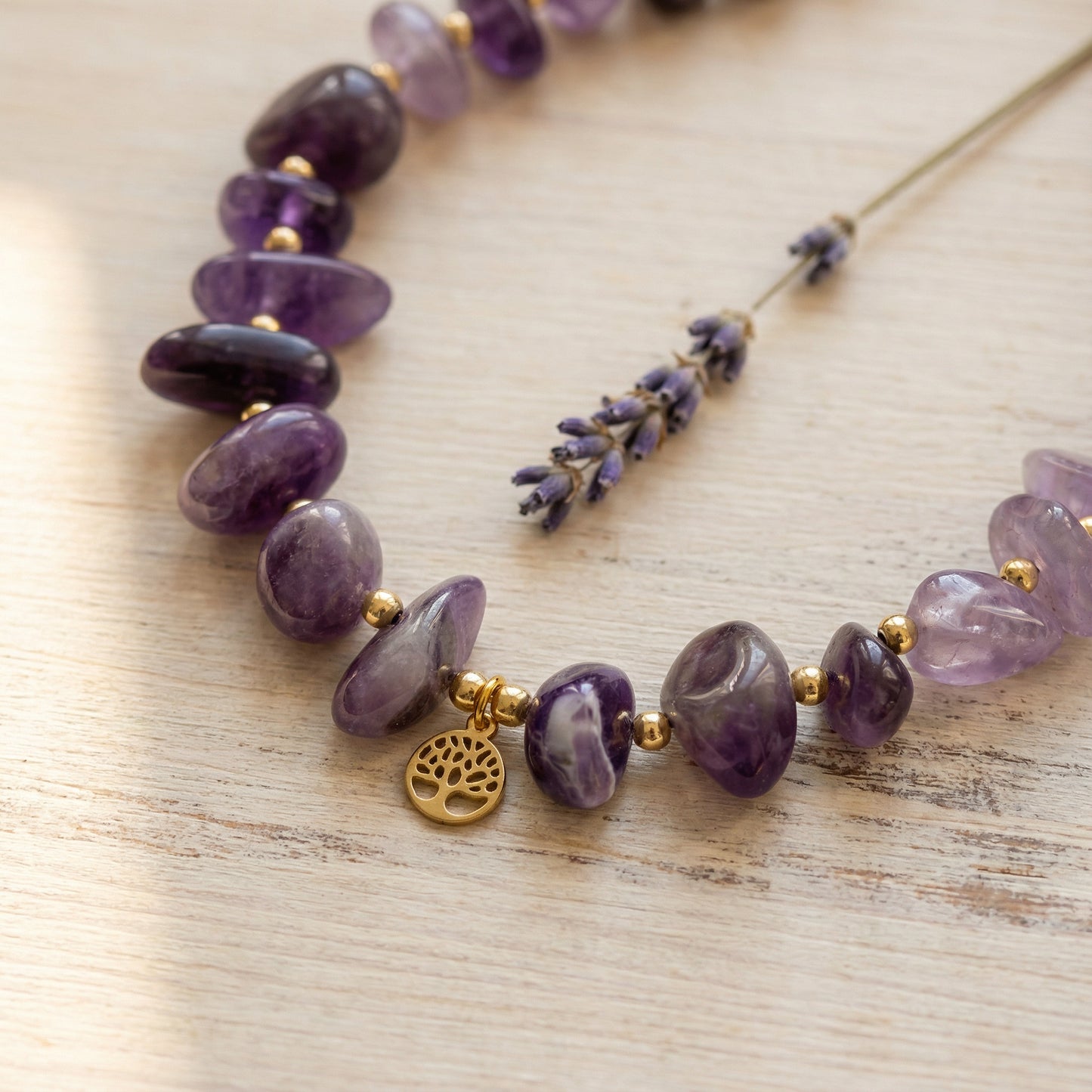 Necklace with purple beads and a gold charm on a wooden surface