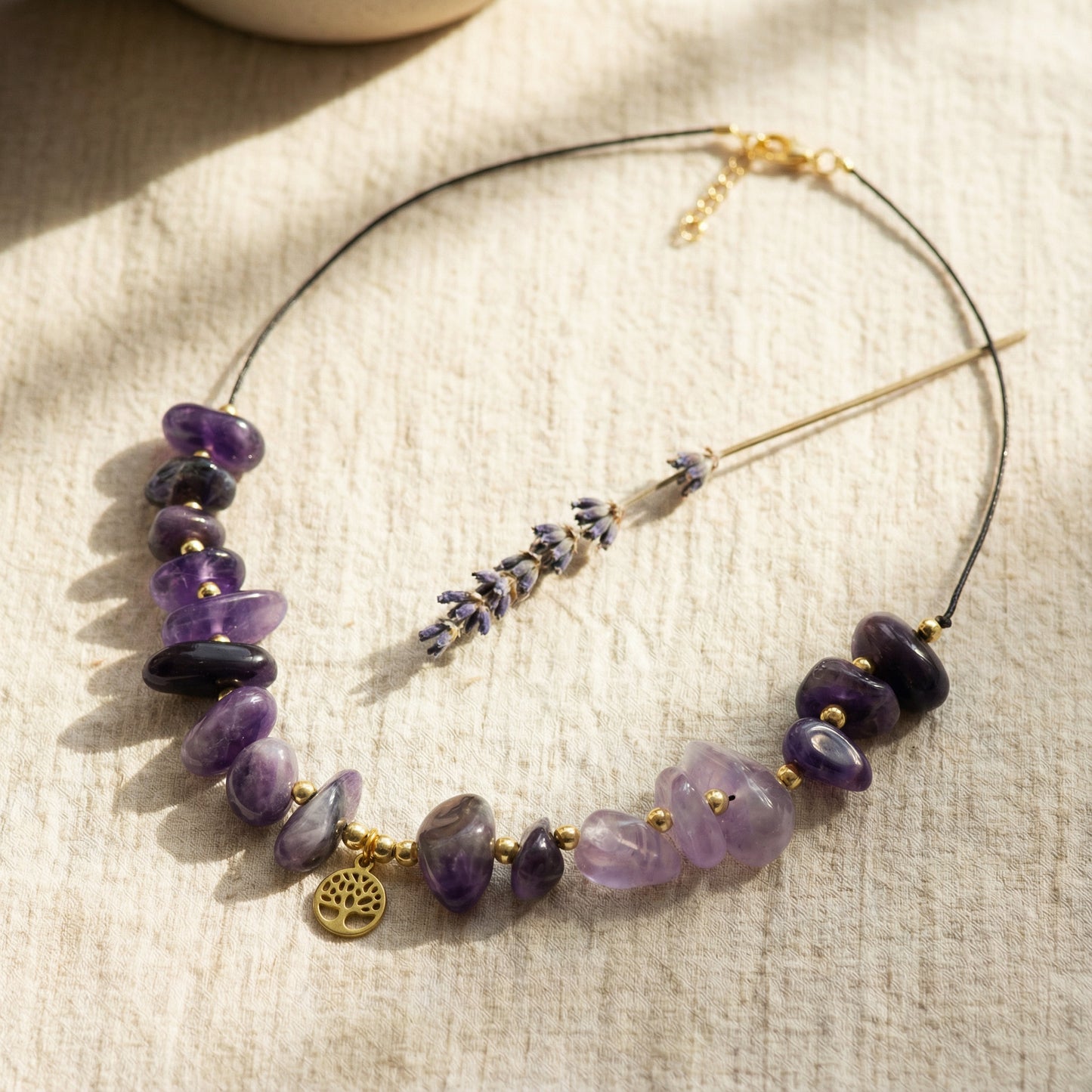 Necklace with purple beads and gold accents on a textured fabric background