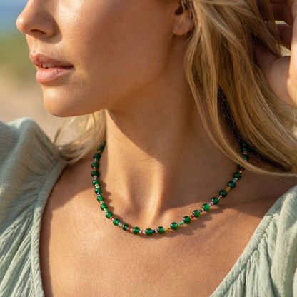 Close-up of a woman wearing a green beaded necklace outdoors