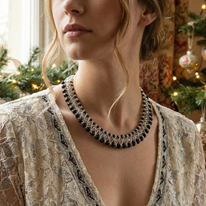 Woman wearing a black beaded necklace with a blurred festive background