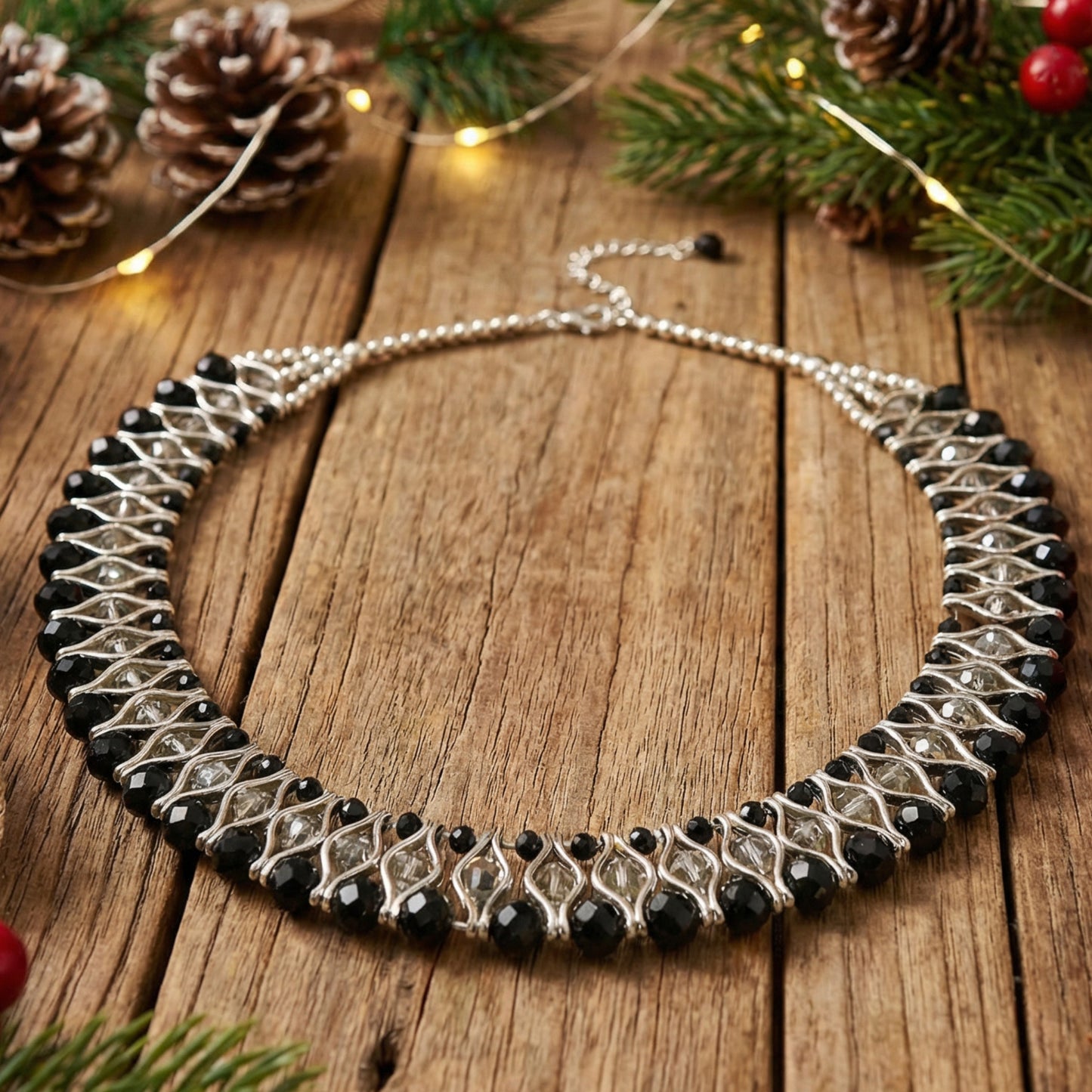 Necklace with black and silver beads on a wooden surface with Christmas decorations.