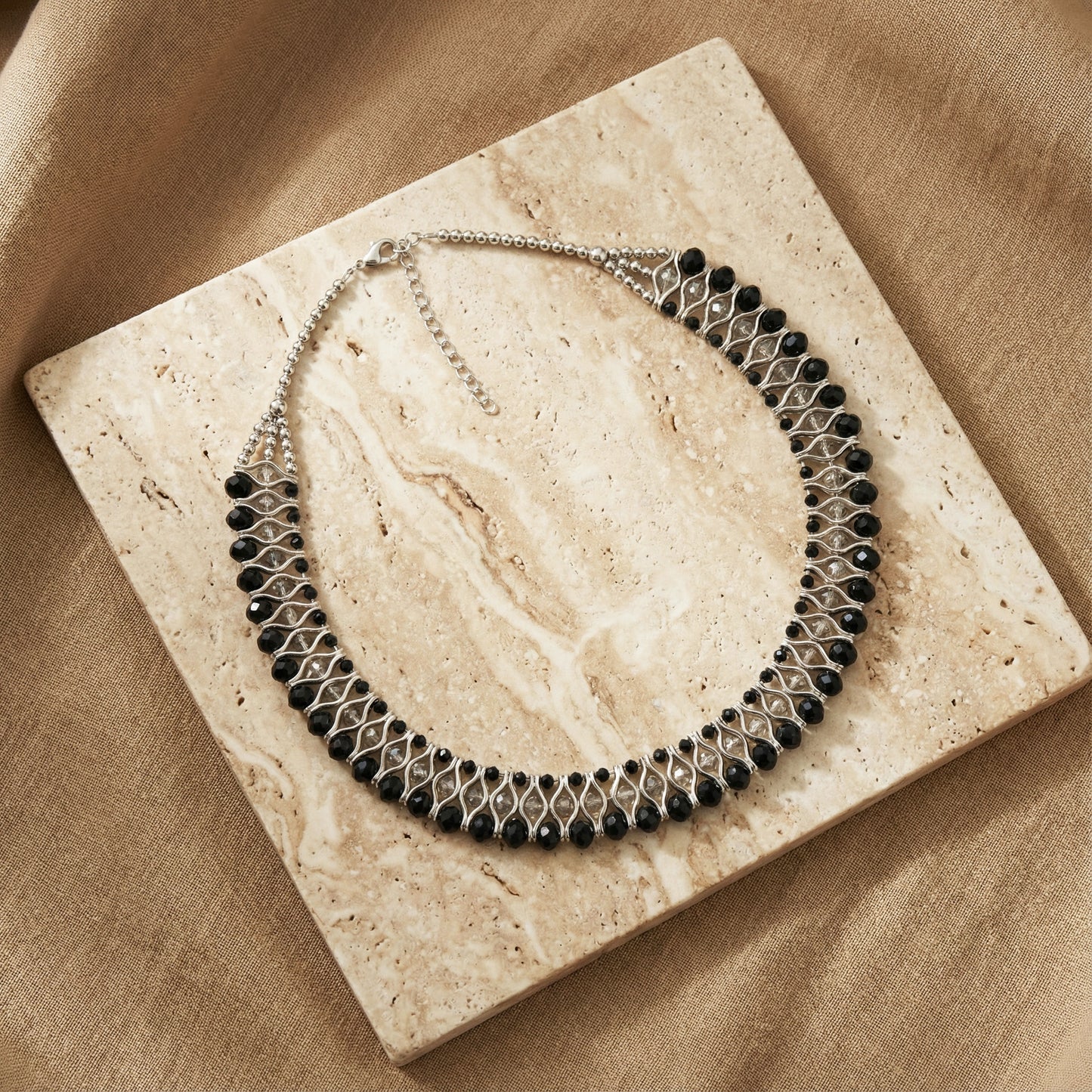 Necklace with black beads on a beige stone surface
