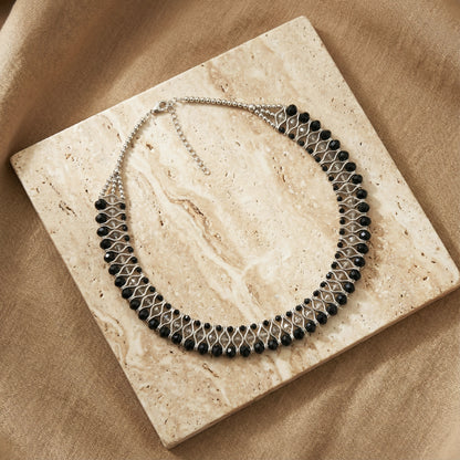 Necklace with black beads on a beige stone surface