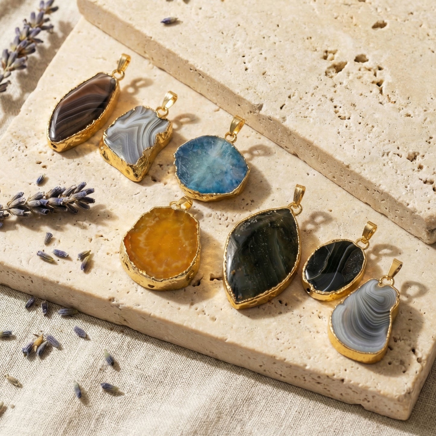 Set of stone pendants on a textured surface with lavender flowers