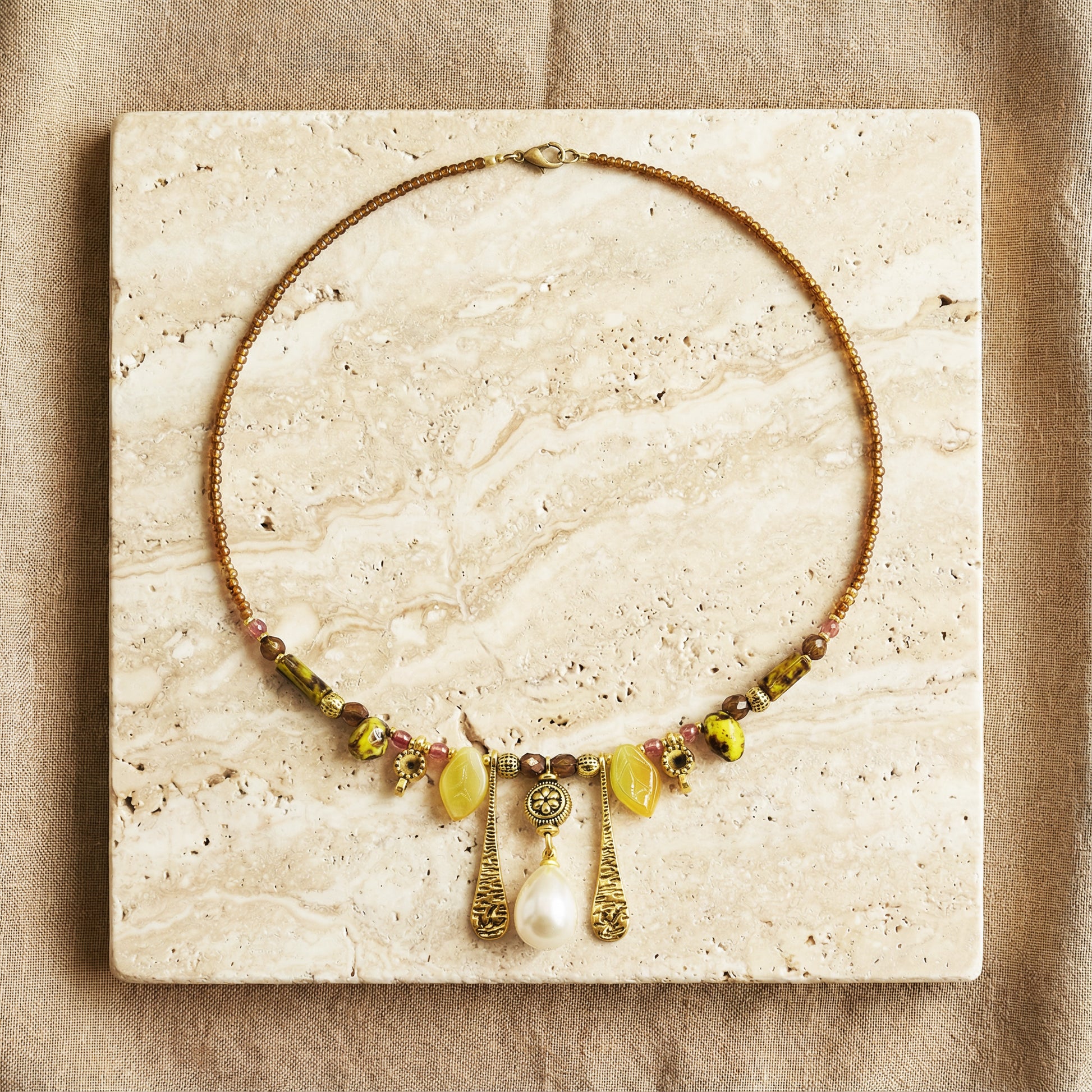 Necklace with beads and pendants on a textured stone surface