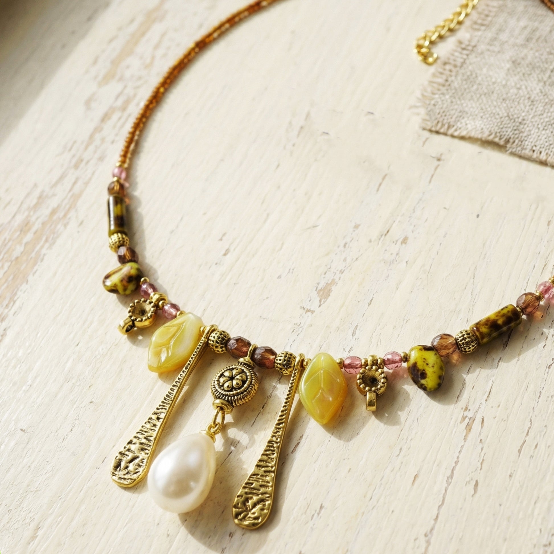 Necklace with beads and charms on a light wooden surface