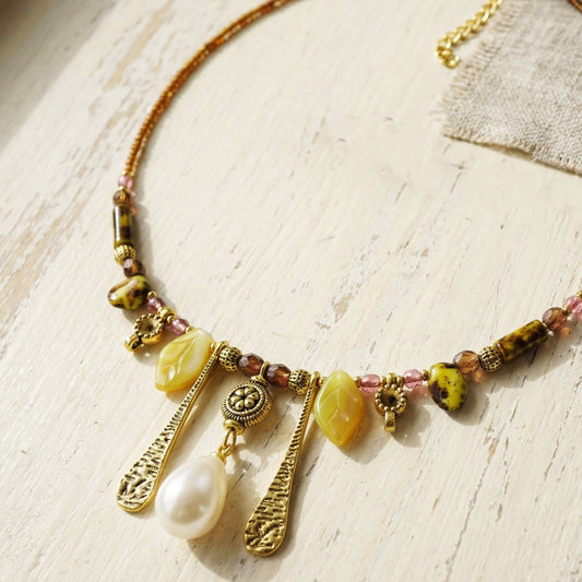 Necklace with beads and charms on a light wooden surface